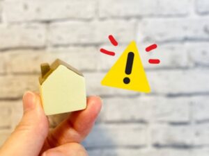 家のミニチュアと警告マーク